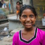 India - Slums - One Child - Girl smiles water filters